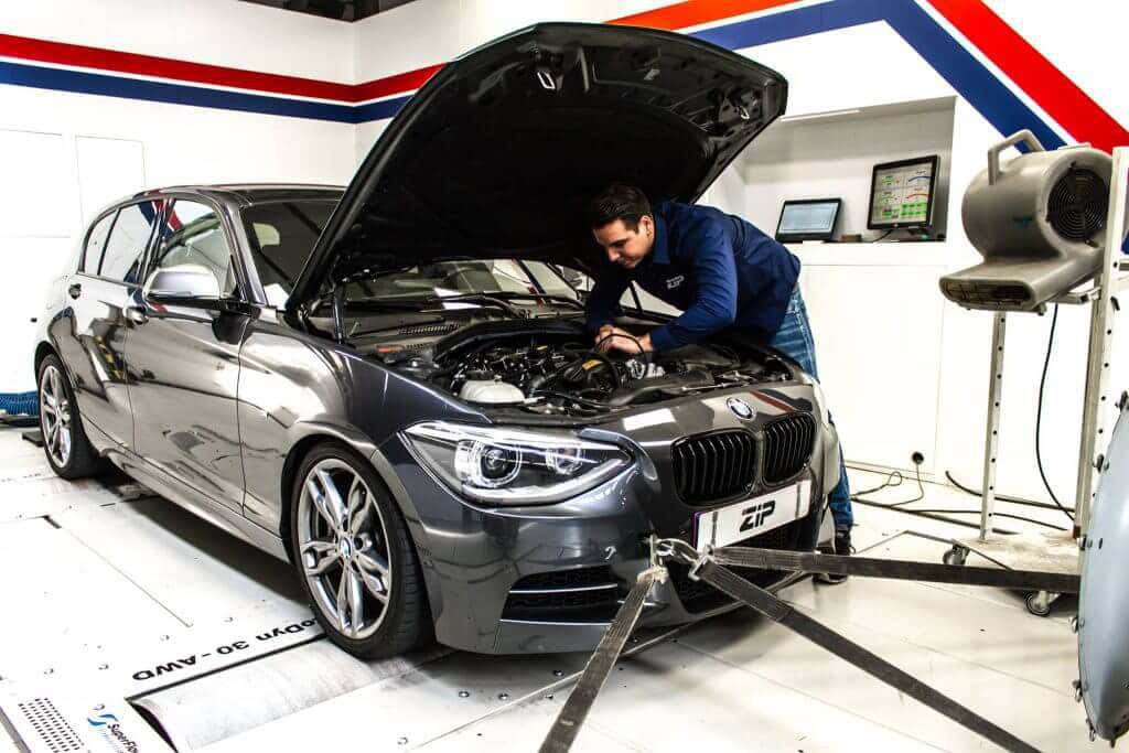 Engineer aan het werk onder de motorkap van een BMW op de rollenbank